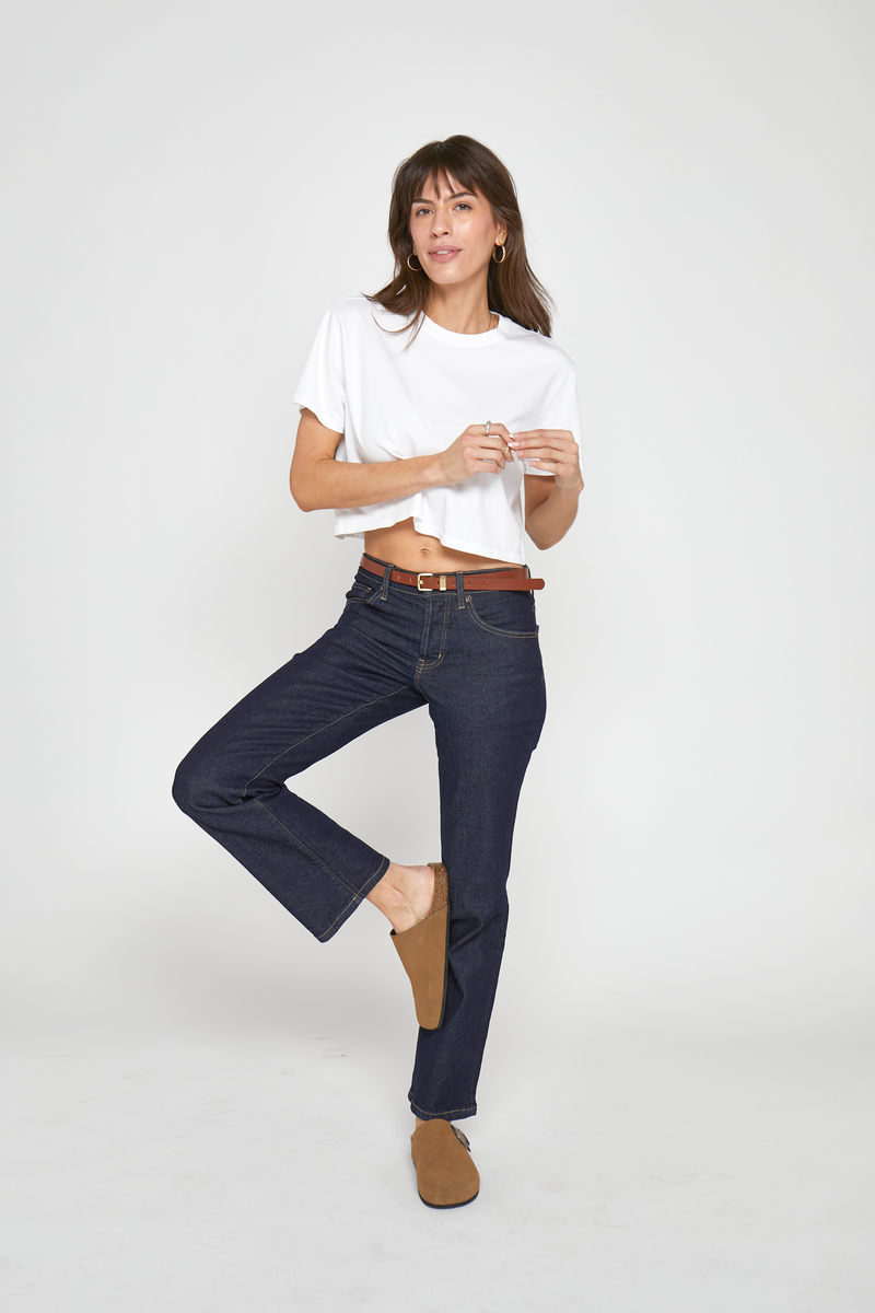 Model is standing with one foot raised, displaying the comfortable, flattering fit of the bootcut jeans. She is facing forward.