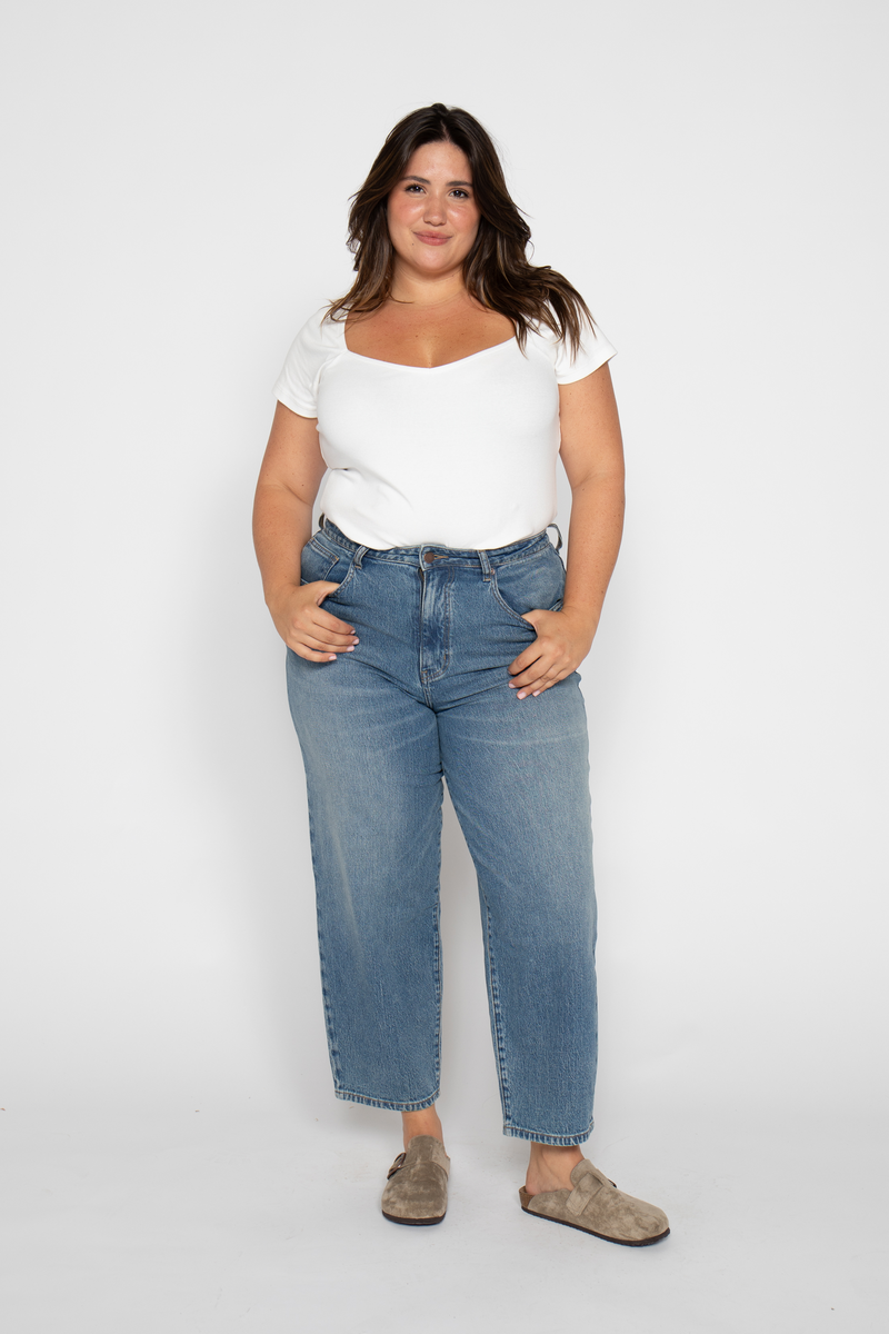 Plus-size model standing confidently in high rise wide leg cropped jeans, highlighting barrel leg comfort and versatile style.