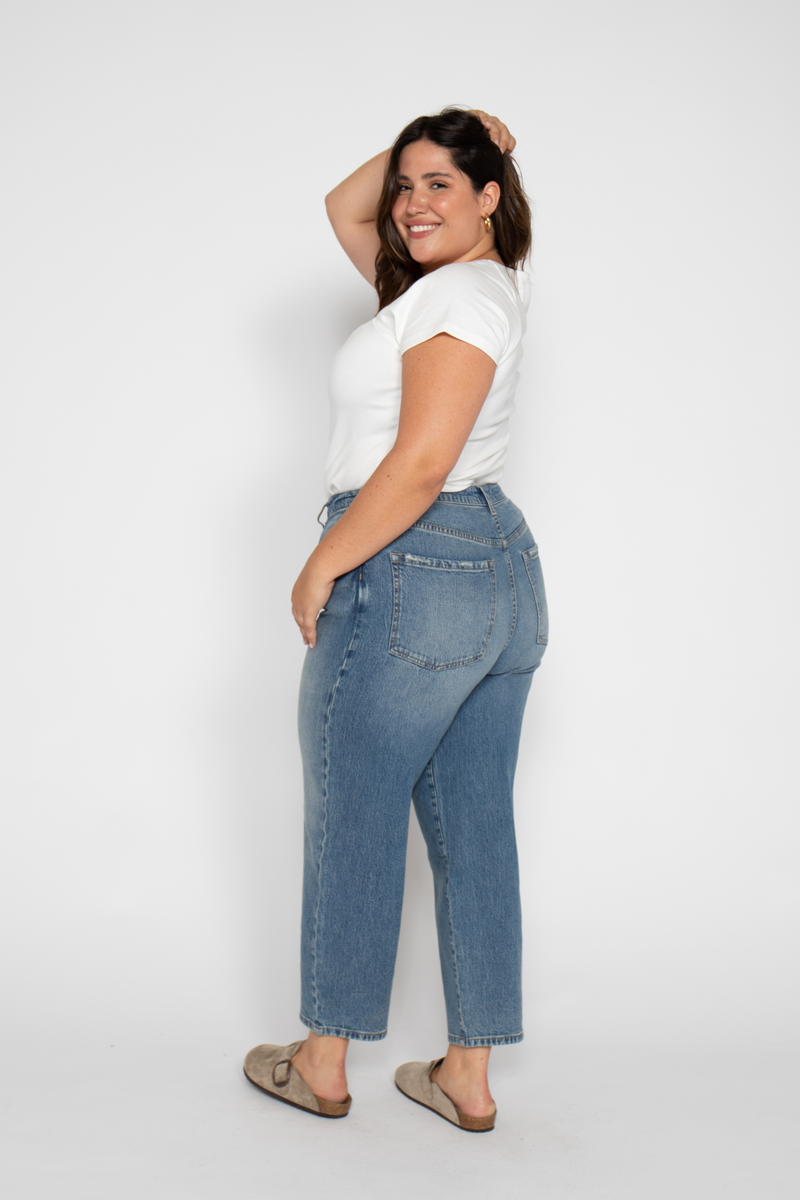 Back view of plus-size model in barrel leg jeans, emphasizing the wide leg crop cut and flattering high rise fit.
