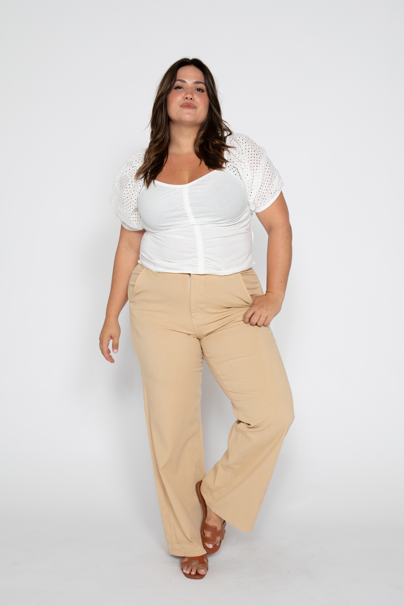 Plus-size model styled in beige wide-leg trousers, showing casual and comfortable fit, back view.