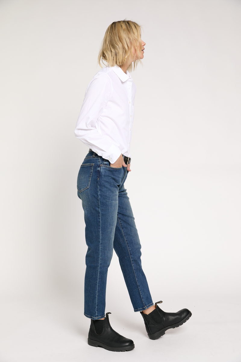 Side view of the model wearing straight legged jeans in dark-wash denim. The vintage look offers a timeless and versatile appeal.