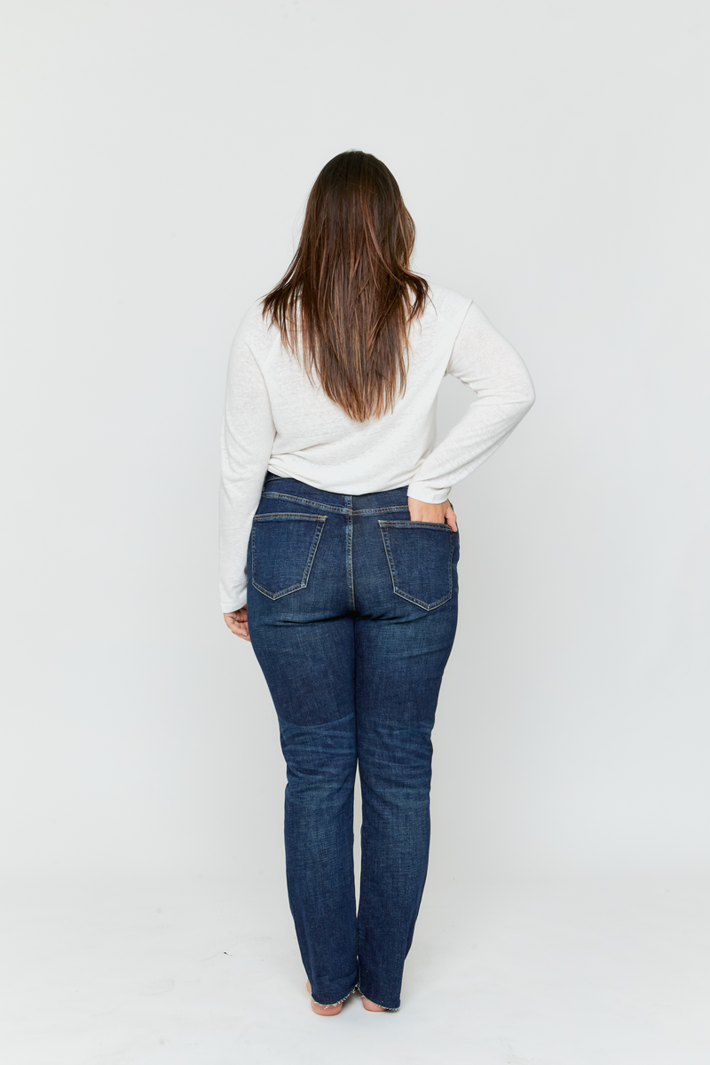 Back view of plus-size model in high rise straight leg jeans, showcasing the flattering fit and classic dark wash.