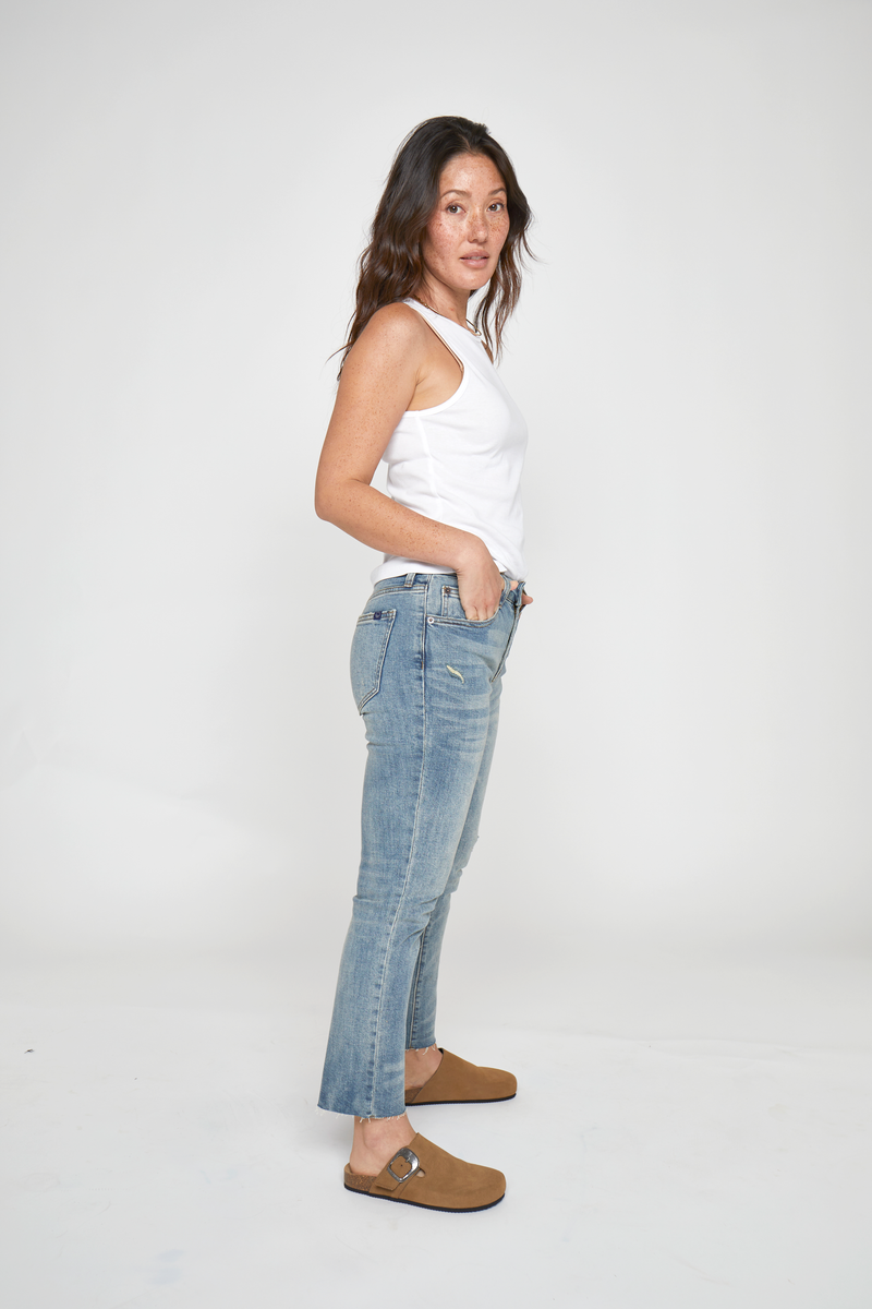 Petite model posing confidently in high rise straight leg jeans, displaying the vintage-inspired denim and slim silhouette.