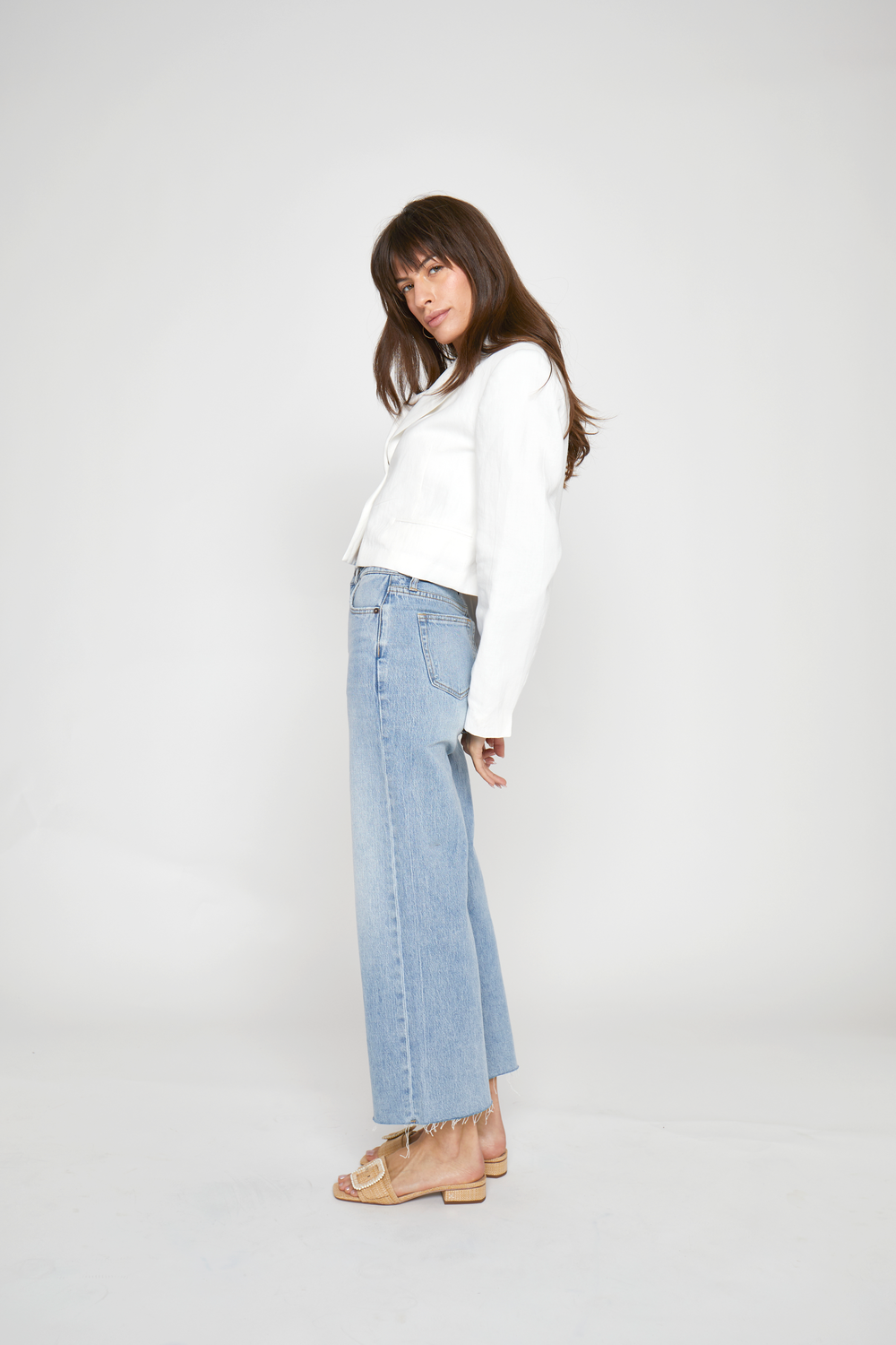 Side view of women's straight fit ankle crop jeans, featuring a structured high-rise waist and deep indigo wash for a modern, polished look.