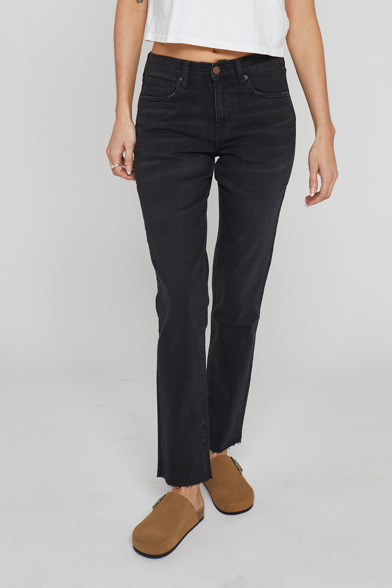 Close-up of black tapered-leg jeans, highlighting the structured silhouette, durable denim fabric, and sleek high-rise waistline.