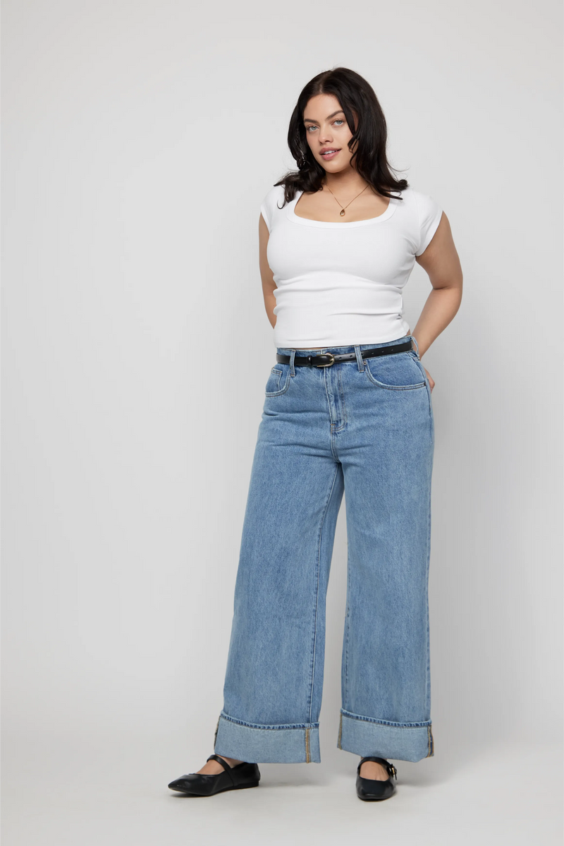 Video of plus-size model walking in mid-rise cuffed wide-leg jeans in a light wash.