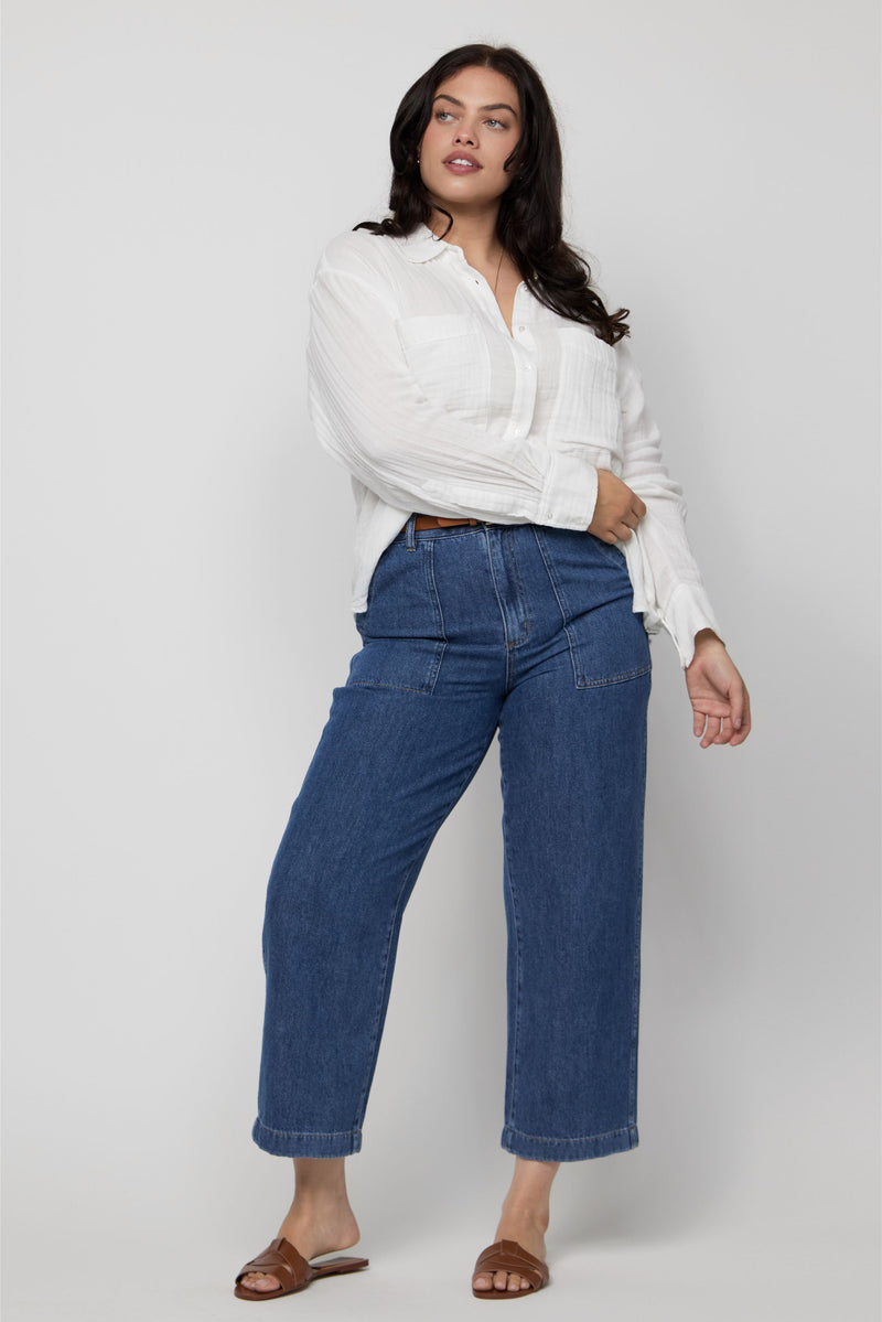 Video of plus-size model wearing high-rise cropped denim trousers in a medium blue indigo wash.