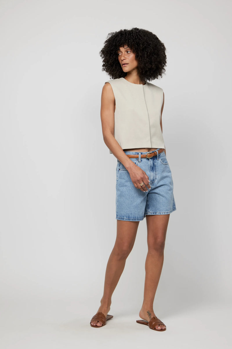 Video of model wearing high-rise light wash jean shorts styled with a sleeveless top and slides.