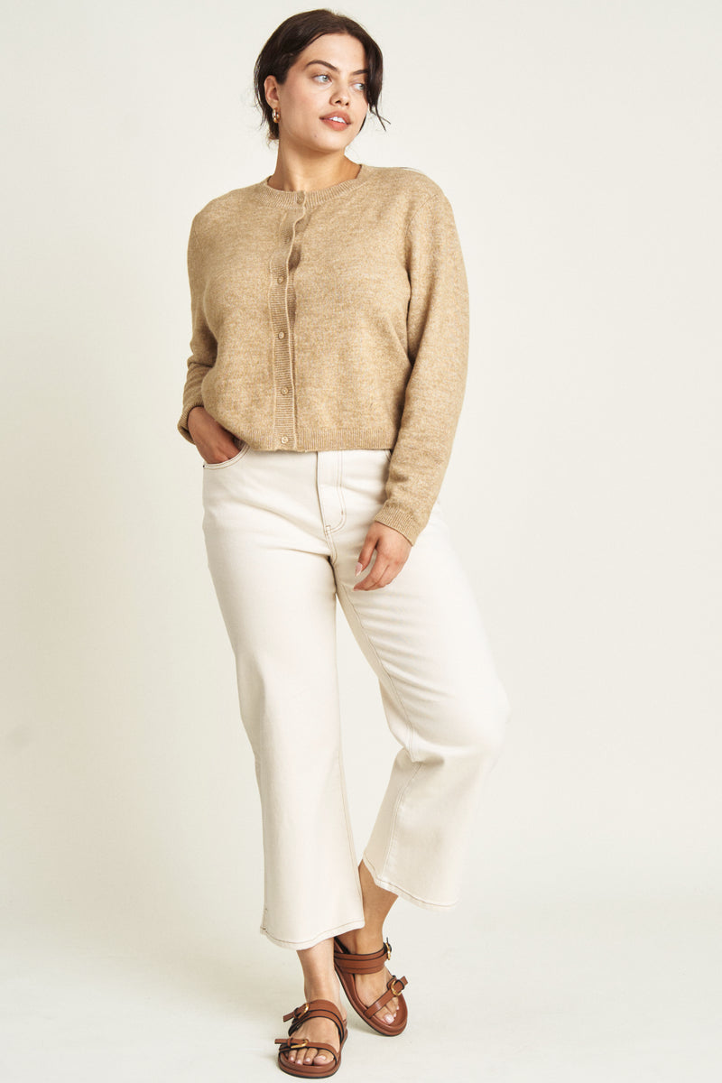 Plus-size model moving in ecru wide-leg ankle crop jeans, demonstrating their comfort and effortless everyday wearability.
