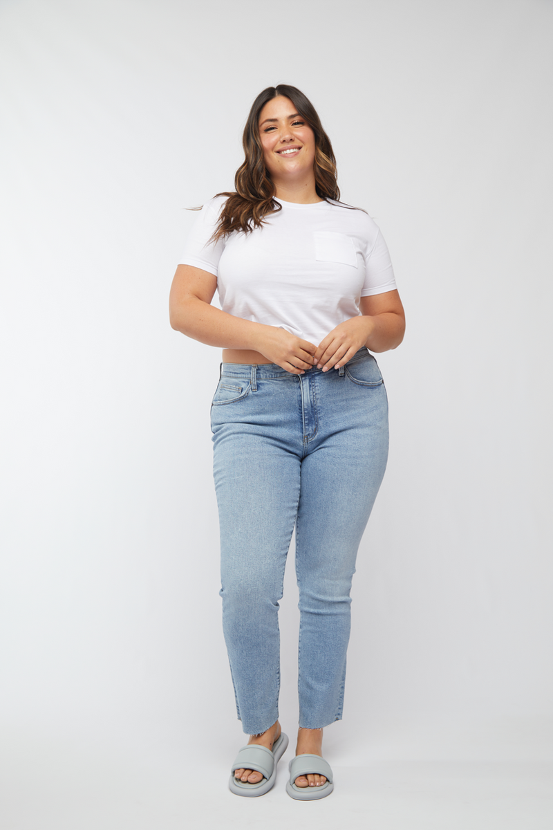 Plus-size model in high rise straight leg jeans, light wash, paired with a white t-shirt, front view showcasing the relaxed fit.