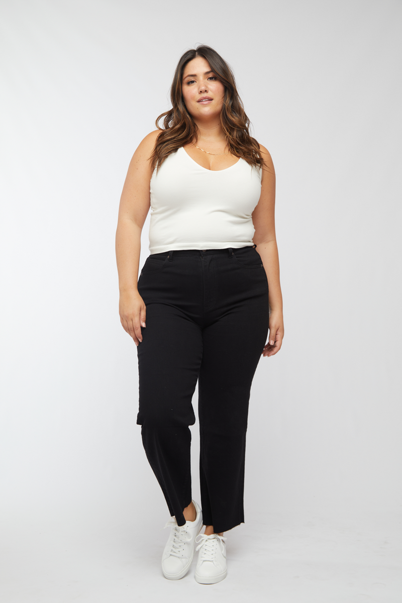 Plus-size model wearing black wash cropped wide leg jeans with a white tank top, front view showing the relaxed fit.