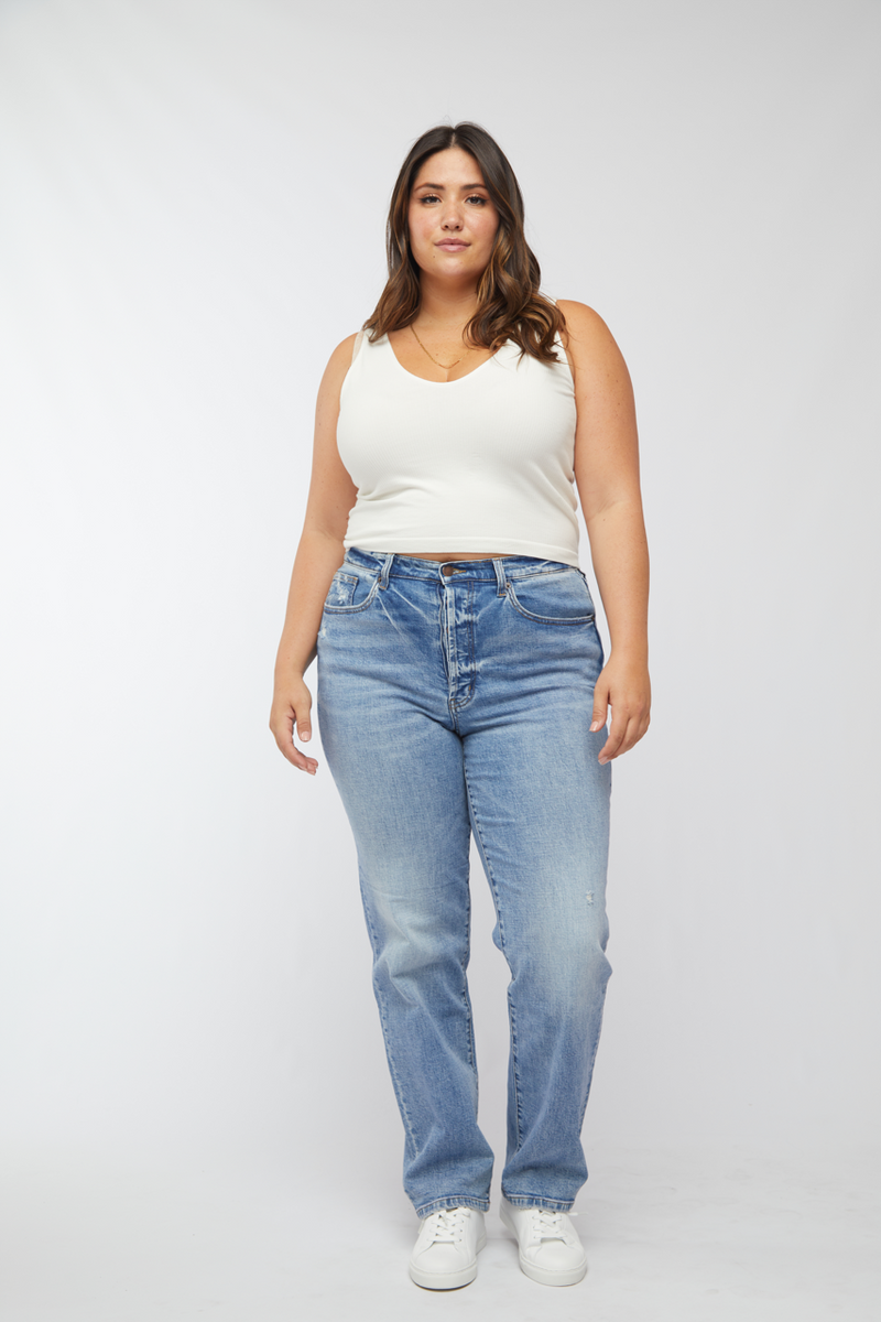 Plus-size model wearing high rise straight leg jeans, light washed denim, paired with a white tank top, front view highlighting the relaxed fit.