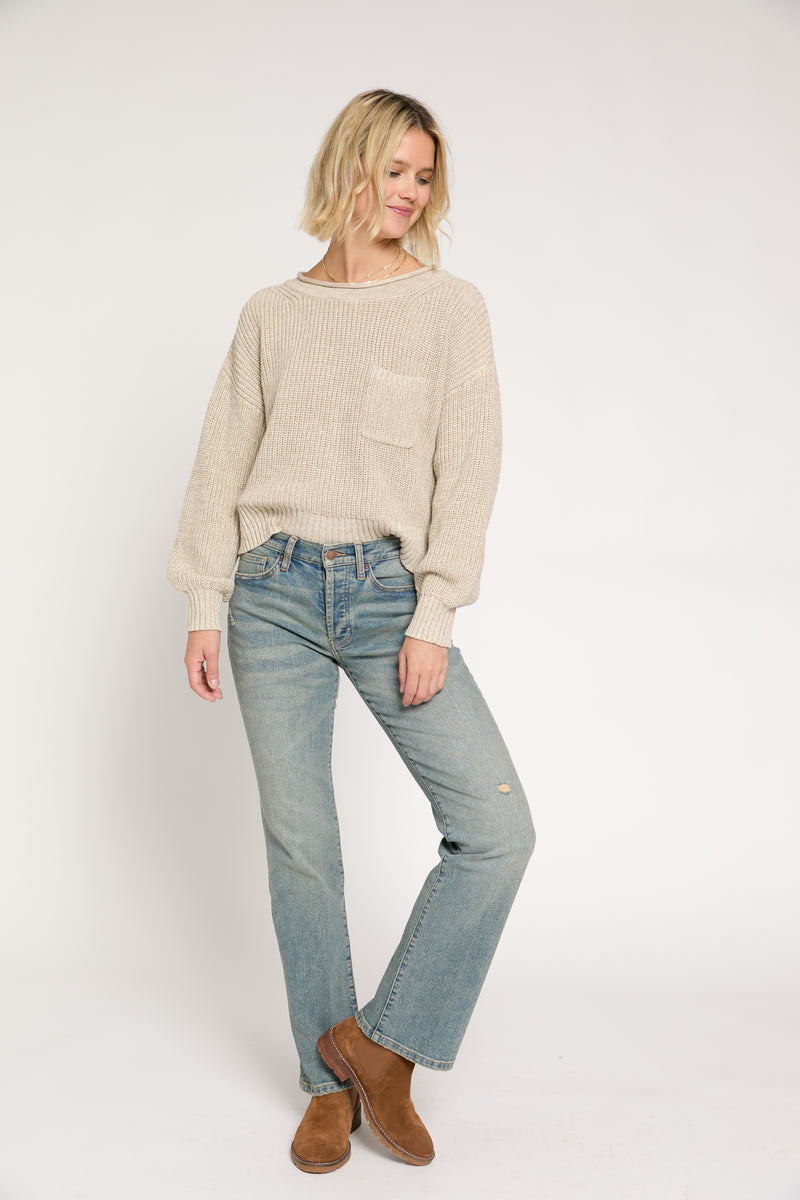 Model seated wearing light vintage wash mid-rise straight-leg jeans, showing the comfortable, casual fit paired with boots.