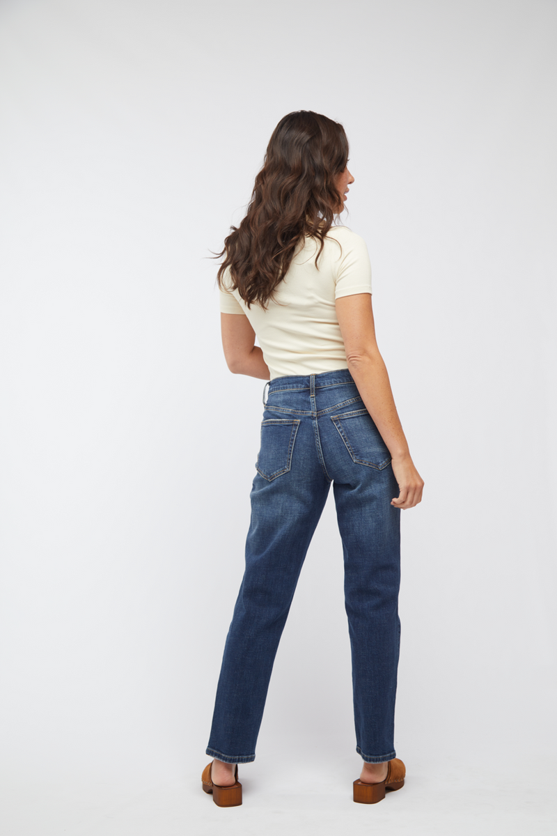 Back view of model in dark wash straight leg denim, showcasing the relaxed fit mid-rise design.