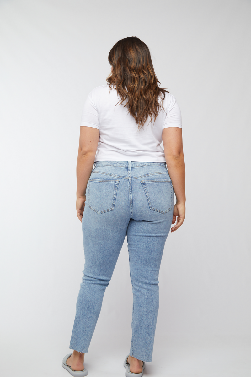 Back view of plus-size model wearing light wash straight leg jeans, highlighting the high rise and flattering silhouette.