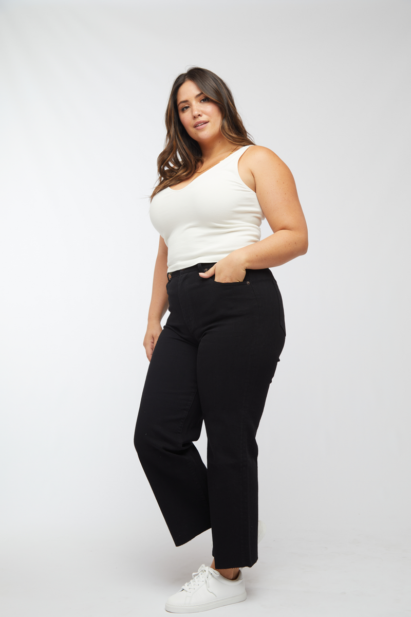 Side view of plus-size model in black wash wide leg cropped jeans, paired with white sneakers, highlighting the casual style.