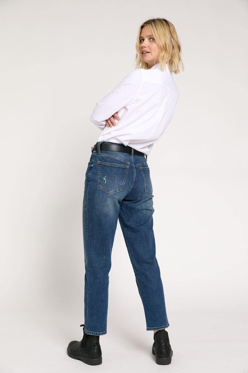 Back view of the model in mid-rise straight leg denim jeans, showcasing clean back pockets and a flattering fit through the hips.