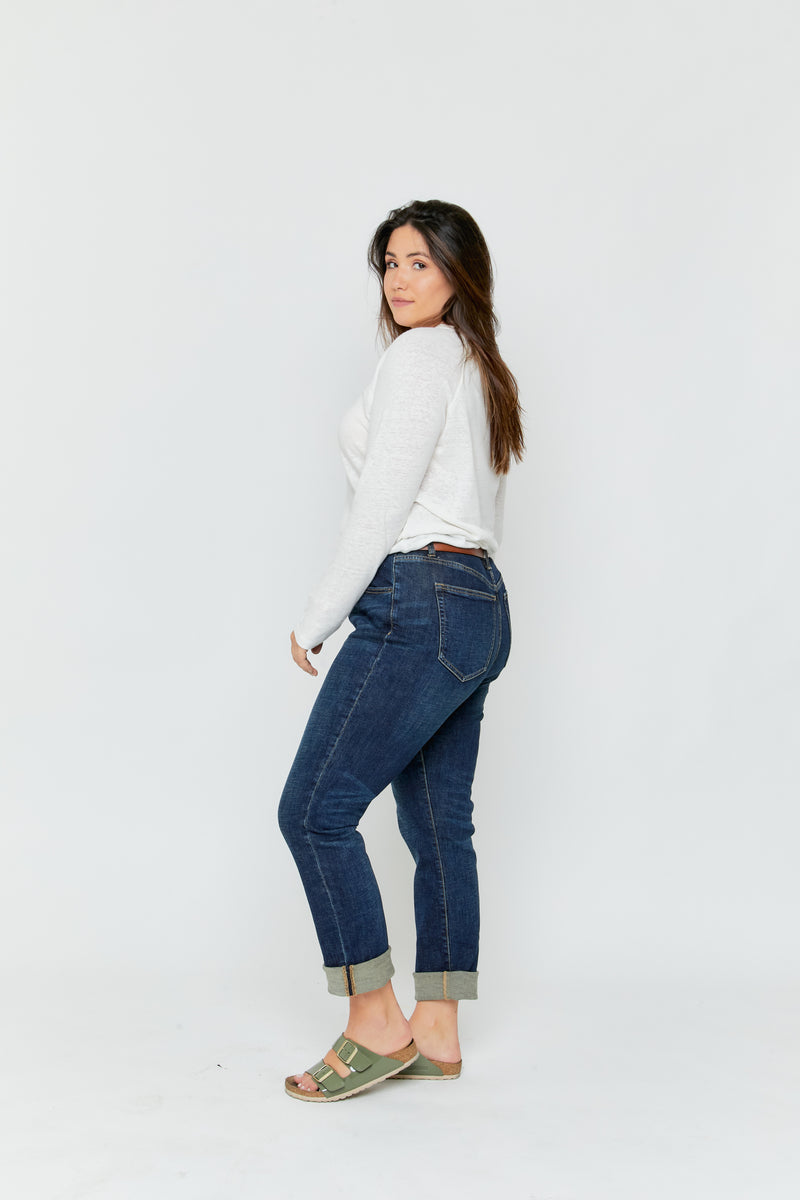 Side view of plus-size model in dark denim straight leg jeans, styled with green sandals, highlighting the high rise and comfortable design.