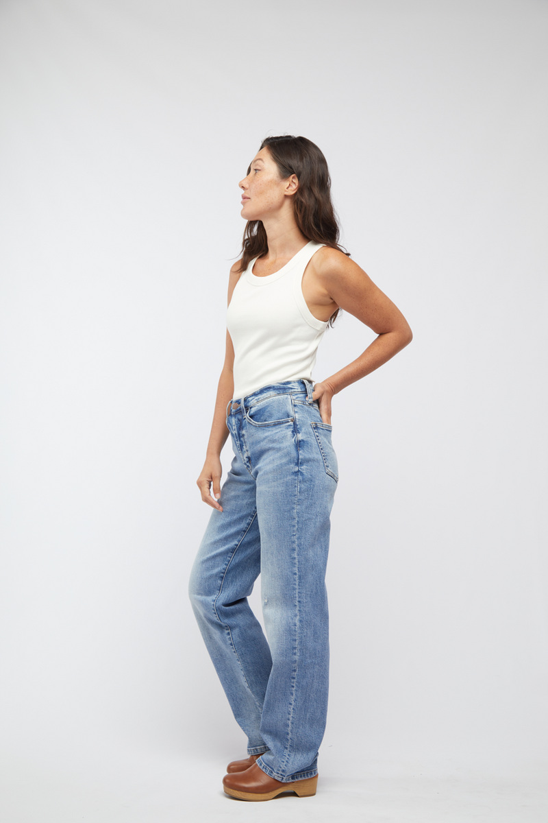 Side view of model in light washed jeans, showing off the high rise and straight leg silhouette with casual brown shoes.
