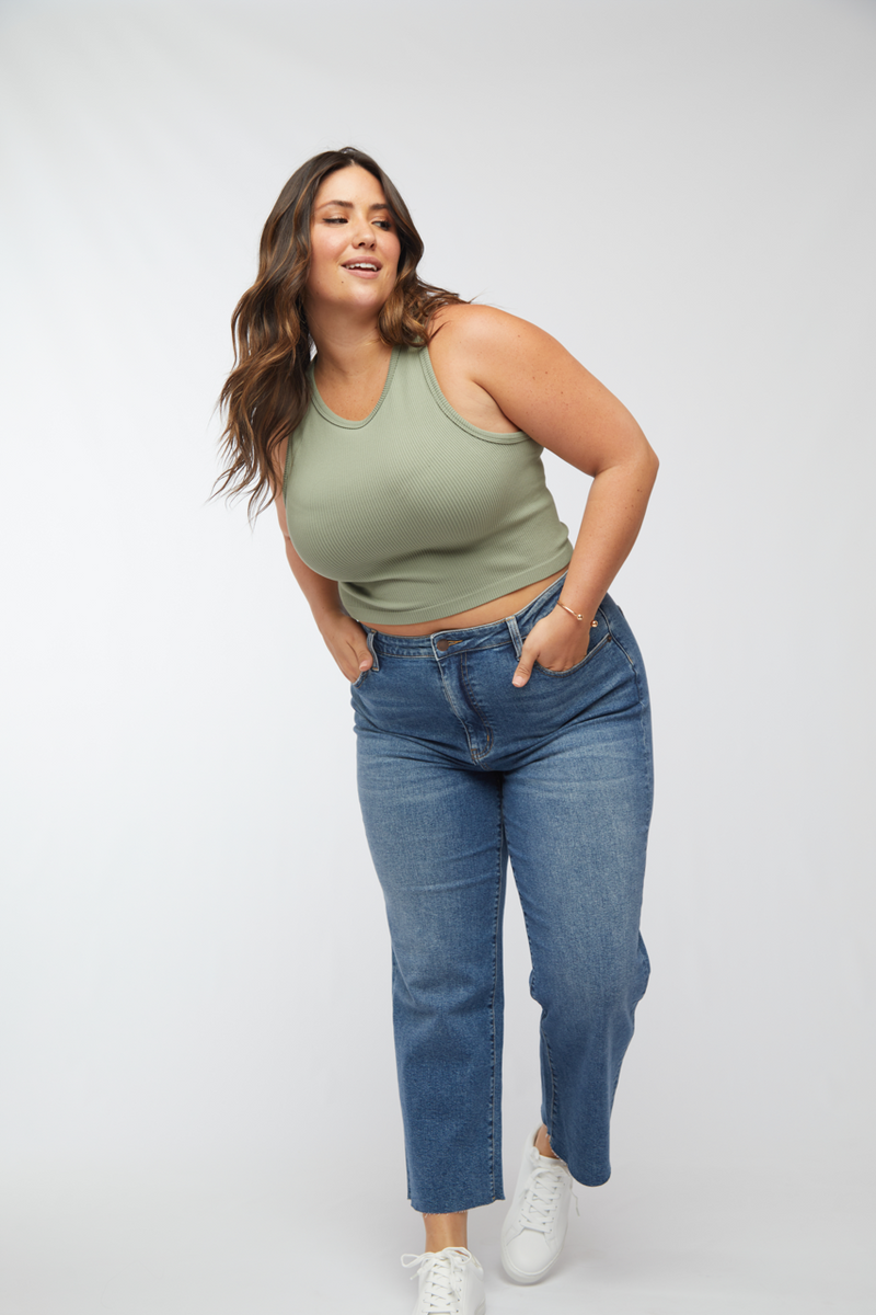 Plus-size model posing confidently in light wash wide leg cropped jeans, showing the stylish and comfortable fit from the side.