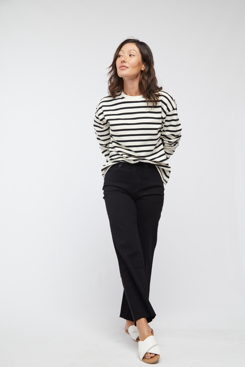 Model posing confidently in black wash high waisted wide leg jeans, paired with a striped top, highlighting the casual chic style.