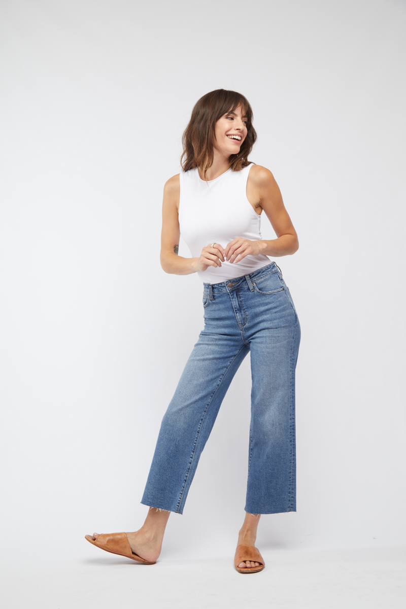 Model confidently posing in light wash wide leg cropped jeans and a white top, displaying the effortless summer style.
