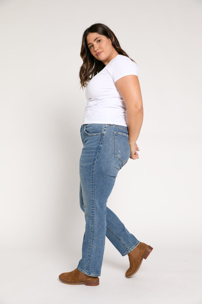 Side view of plus-size high-rise straight leg jeans in sustainable denim, showcasing the structured waistband, relaxed fit, and soft stretch fabric.