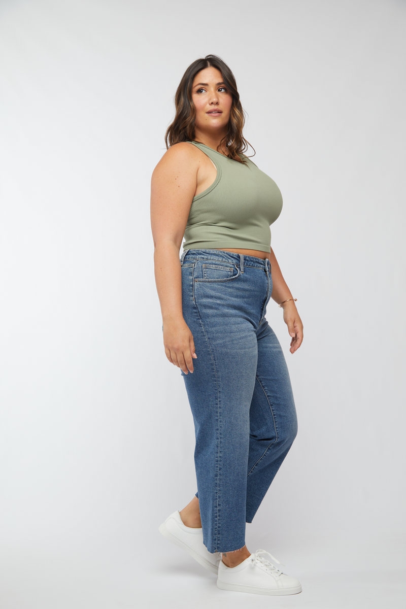 Side view of plus-size model in light wash cropped wide leg jeans, paired with white sneakers, highlighting the casual and comfortable look.