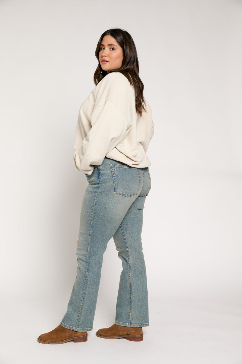 Model casually posing in vintage wash mid-rise straight-leg jeans paired with a neutral sweater and boots.
