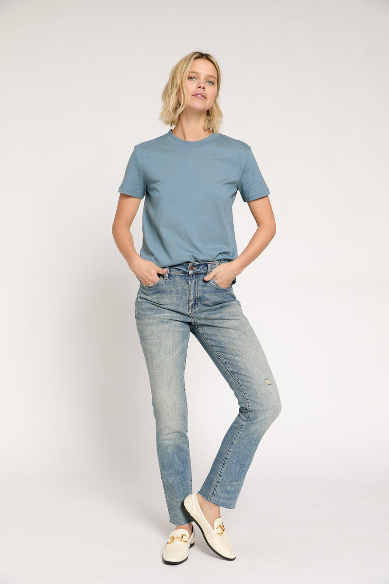 Model styled in high rise straight leg jeans, classic blue wash, paired with a blue tee, front view showcasing a sleek fit.