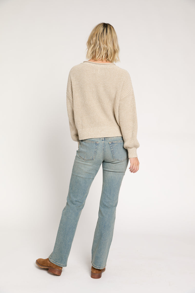 Model standing, hands in pockets, wearing light vintage wash mid-rise straight-leg jeans, perfect for casual wear with boots.