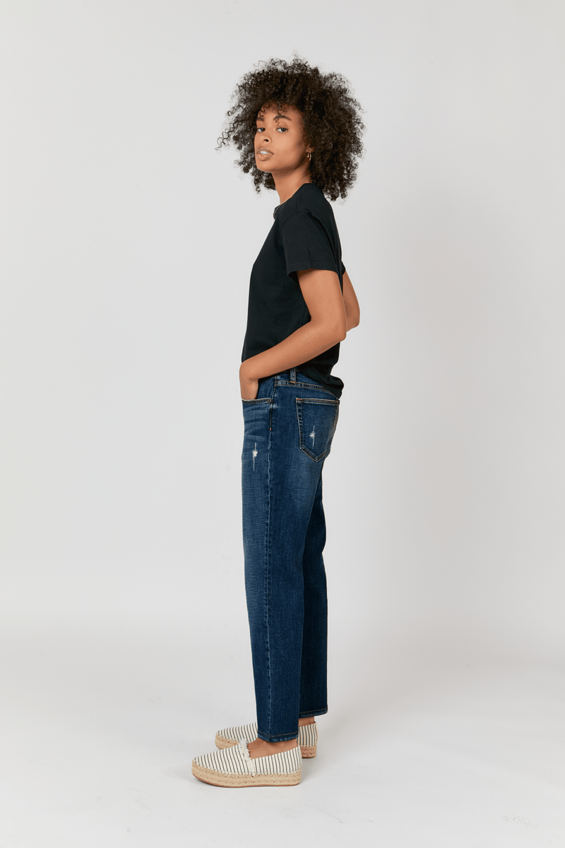 Side view of the model showing the relaxed fit mid-rise jeans, featuring a straight leg cut for casual versatility.