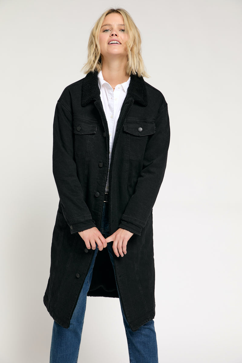 A close-up of the black trench coat, highlighting the vintage sherpa design and button-up front.