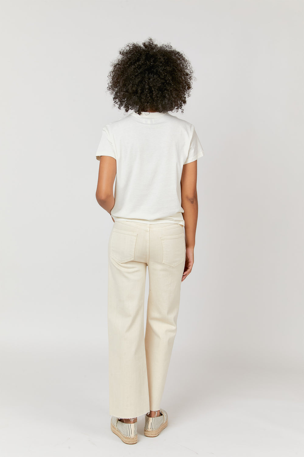 Back view of model in ecru jeans, styled with espadrilles, showcasing the high-rise fit and casual look.