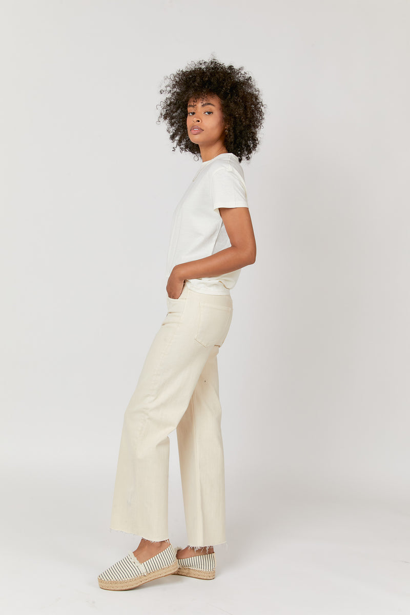 Model posing confidently in ecru high waisted wide leg jeans, paired with a white tee, showing the effortless, relaxed style.