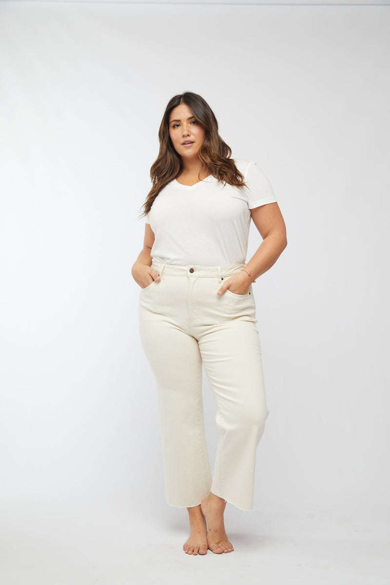 Plus-size model wearing ecru denim wide leg cropped jeans and a white t-shirt, front view highlighting the relaxed fit.