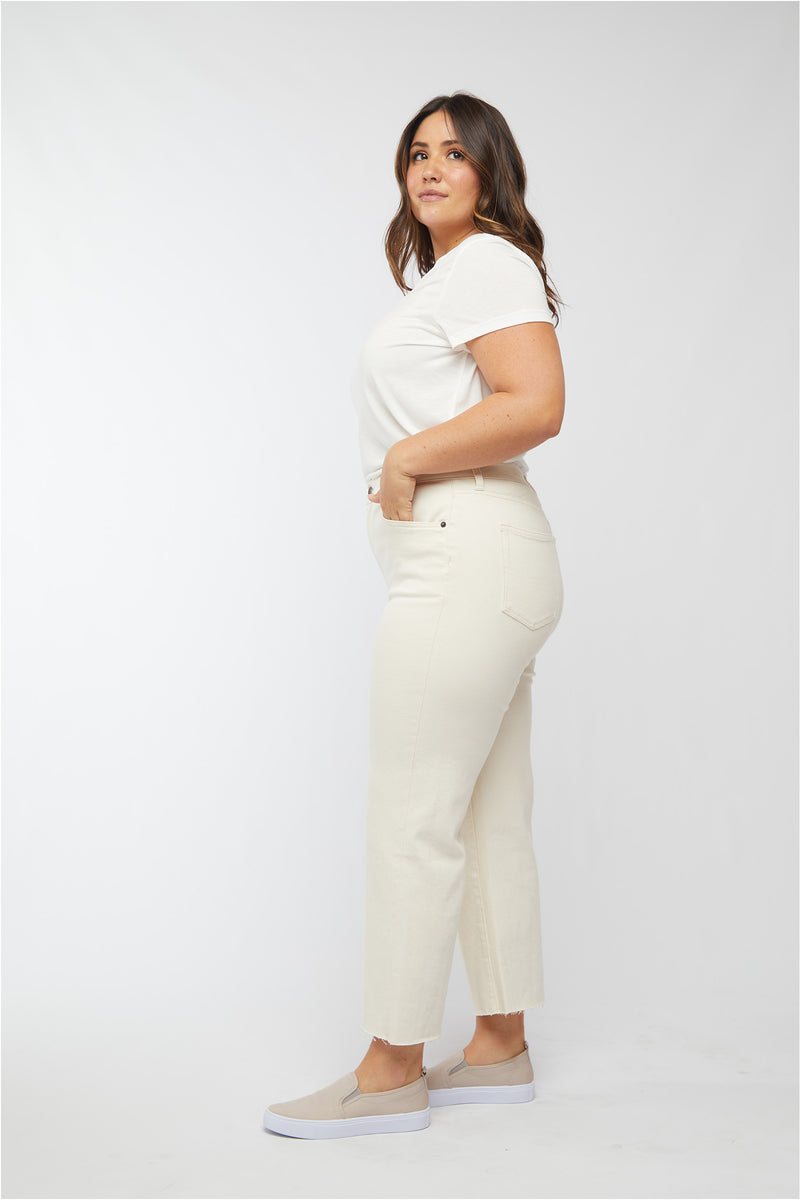 Side view of plus-size model in ecru jeans, paired with slip-on shoes, showcasing the high-rise fit and casual style.