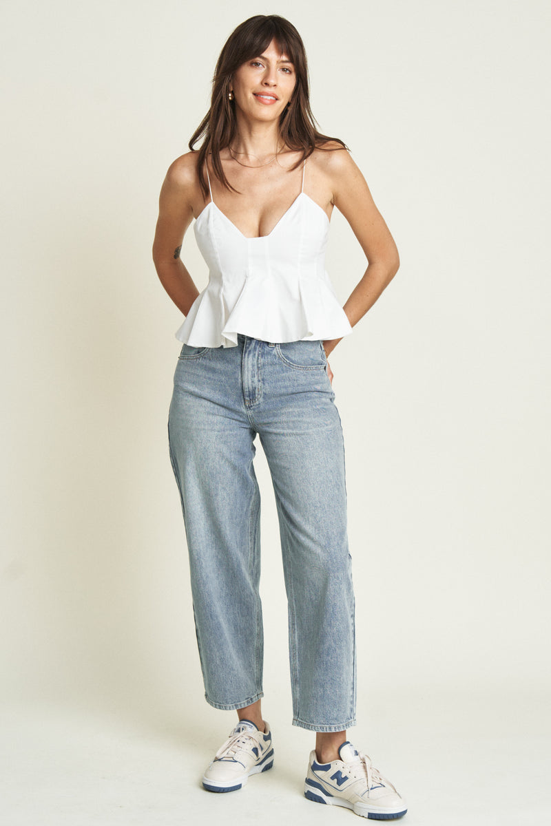 Front view of a model in light-washed barrel jeans paired with a white camisole top, showcasing the casual cropped fit.
