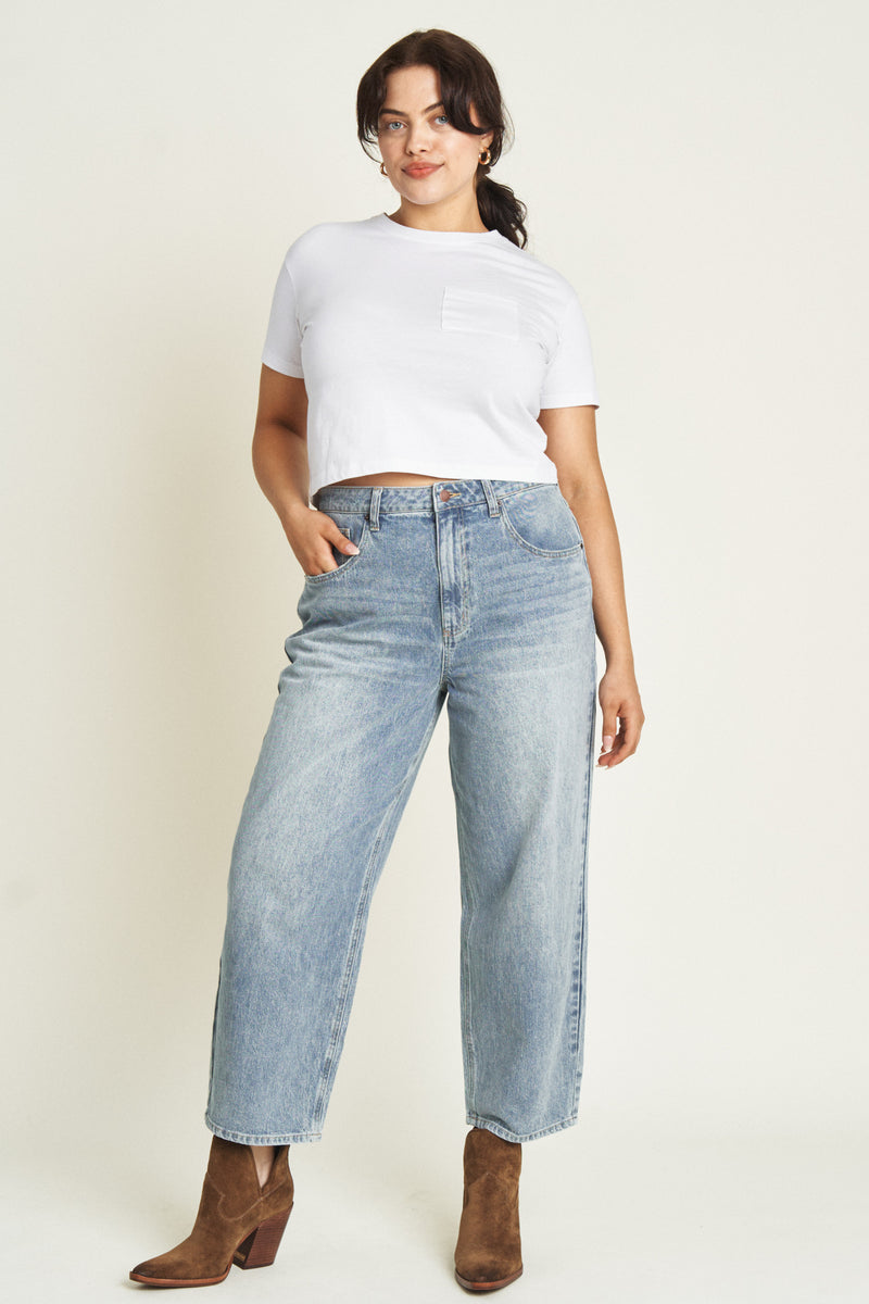 Front view of a model in light-washed barrel jeans paired with a white t-shirt, showcasing the high-rise and wide-leg fit.
