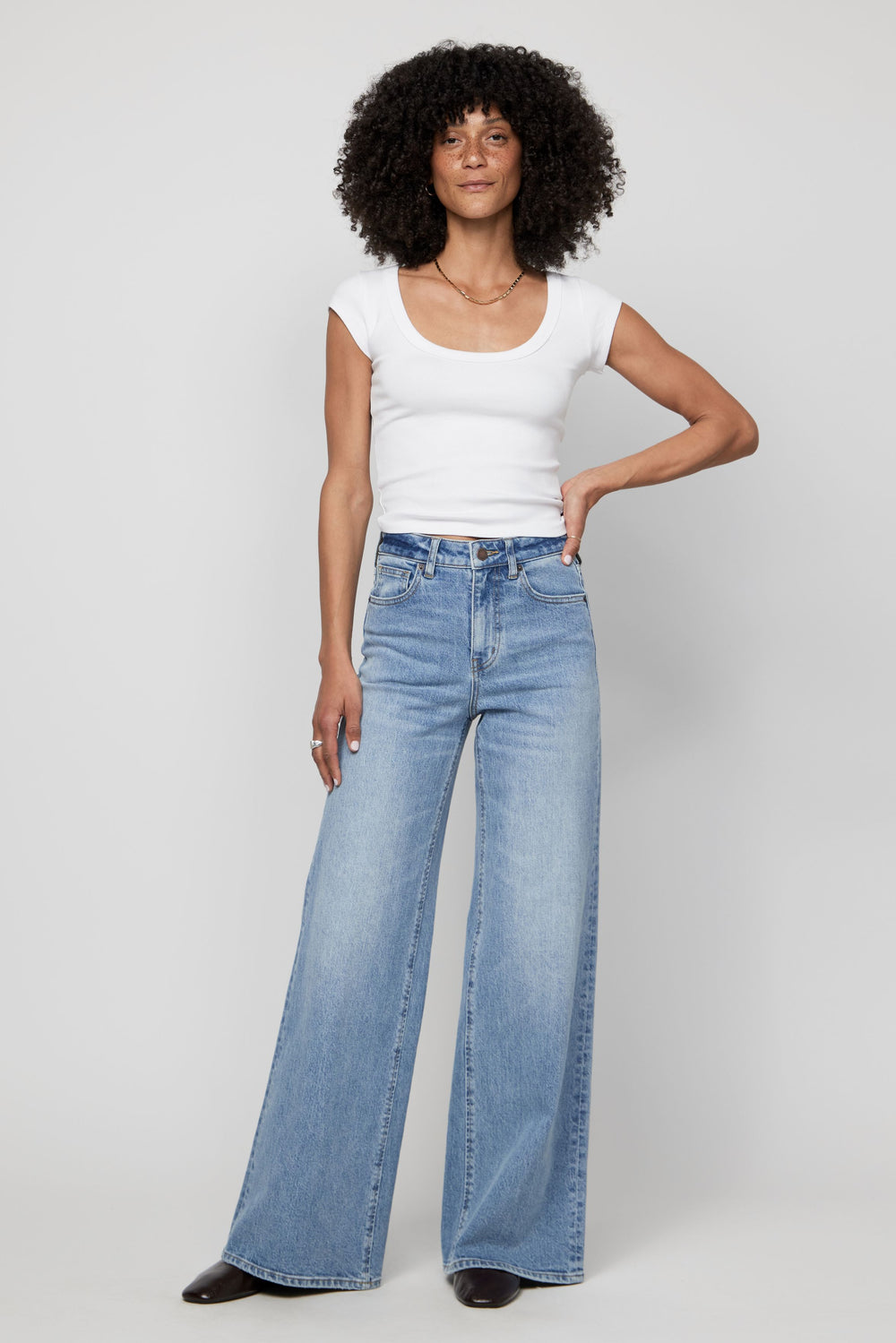 Model wearing high-rise wide-leg jeans with a tucked-in white tank, styled for everyday wear.