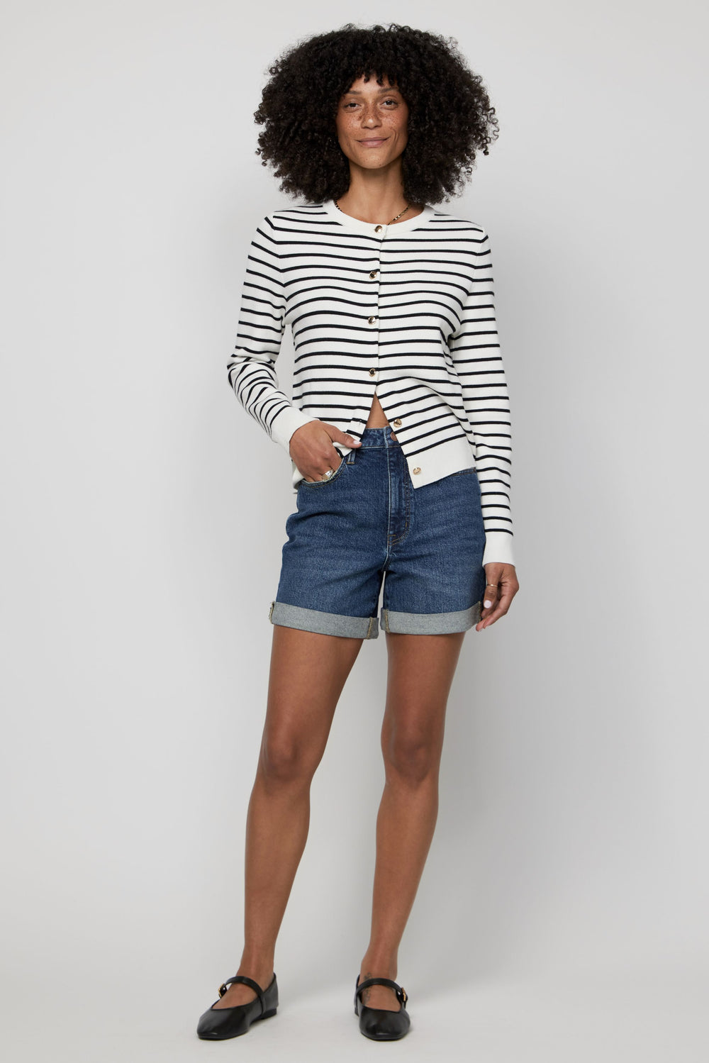Woman wearing high-rise denim shorts in dark indigo with a striped long sleeve top.
