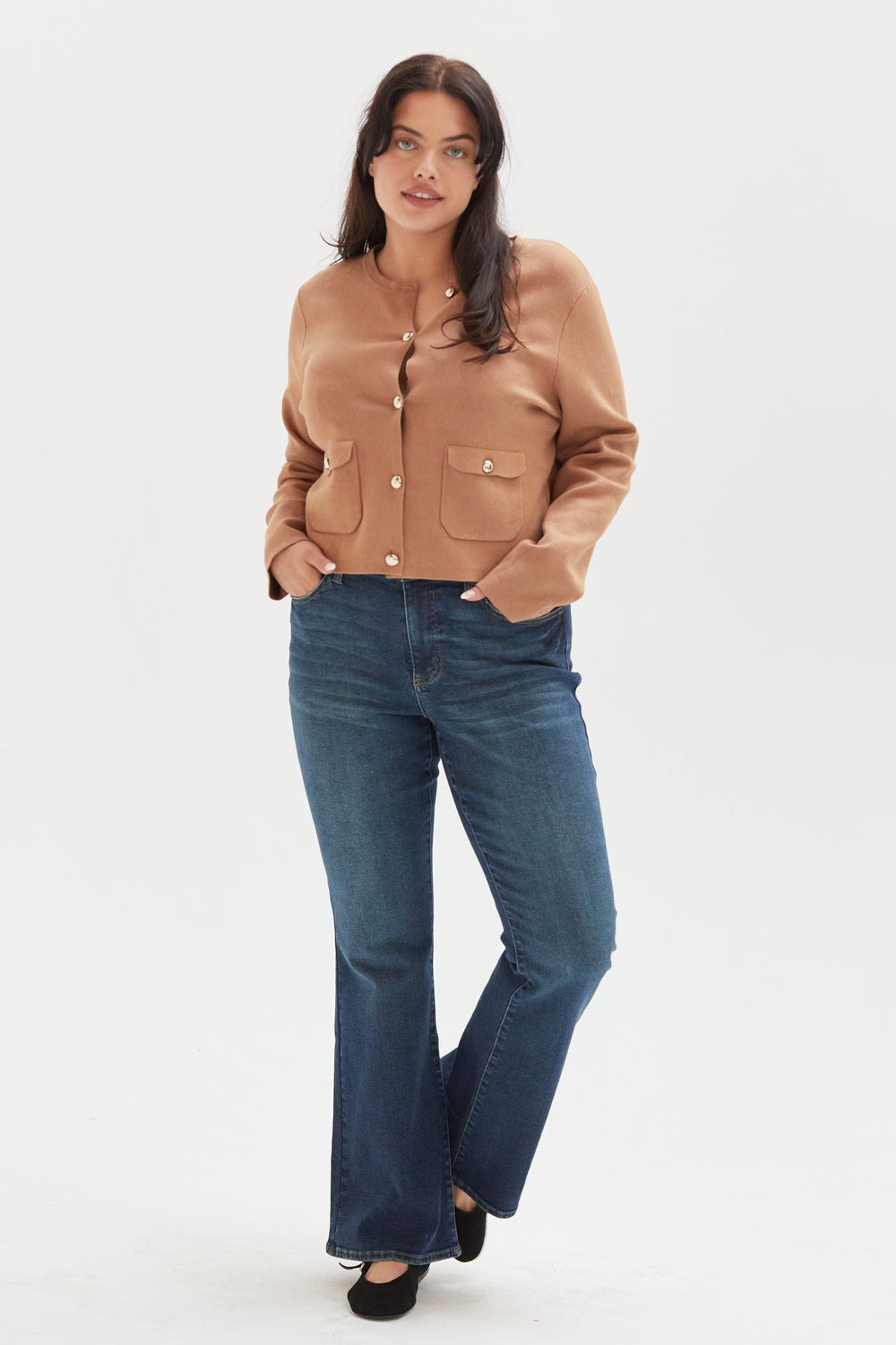 Plus-size model wearing wide-leg ankle crop jeans in an olive overdye wash, styled with a cream ribbed top and black flats, showcasing a relaxed fit and cropped hem.
