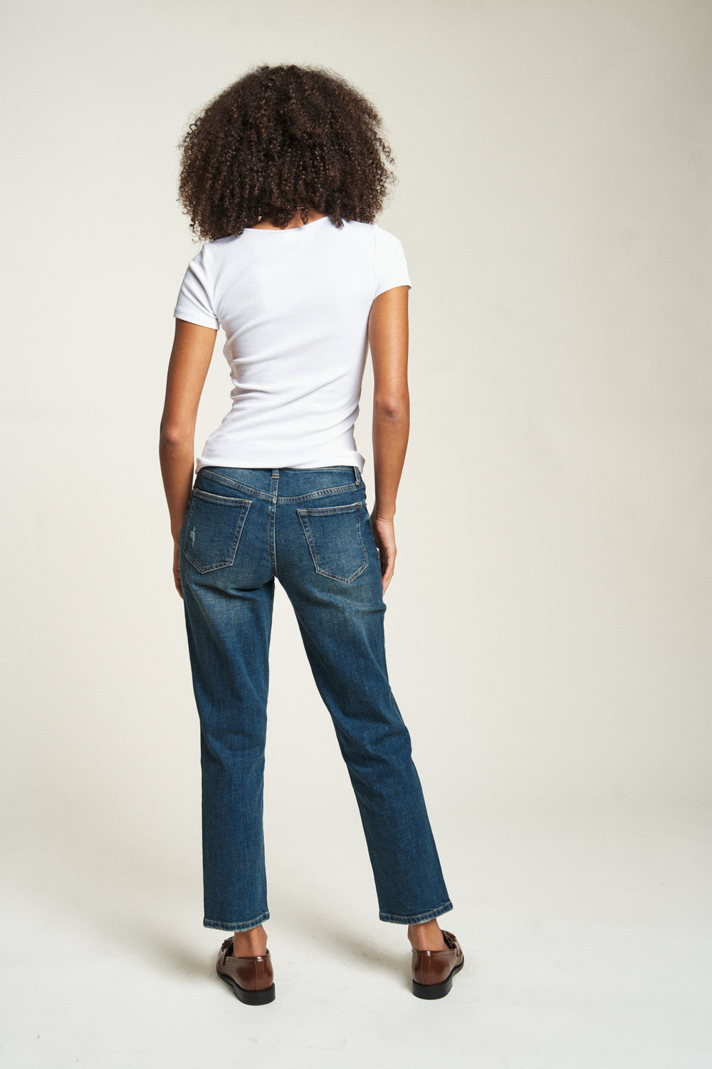 Back view of the model showing straight leg jeans for women in a relaxed mid-rise fit, highlighting the casual yet classic silhouette.
