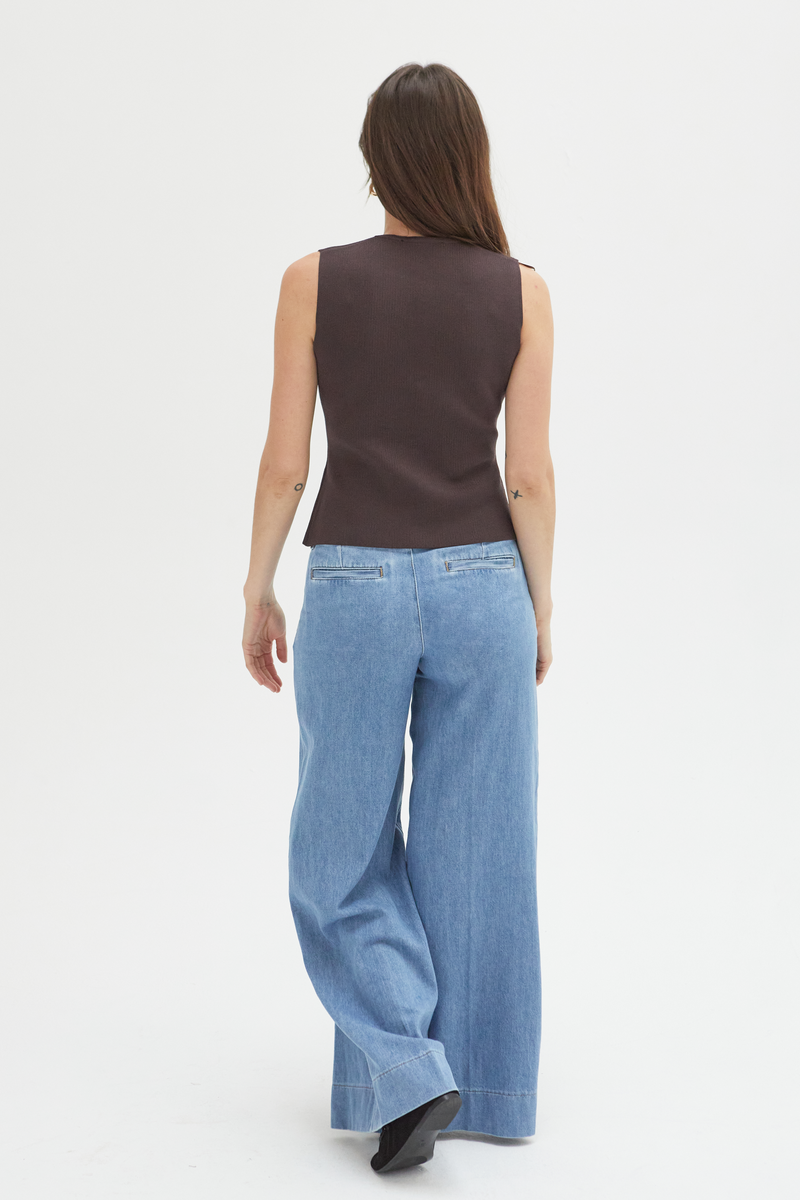 Back view of a model in lighter blue low-rise wide-leg pants, highlighting the pleated detailing and clean lines.
