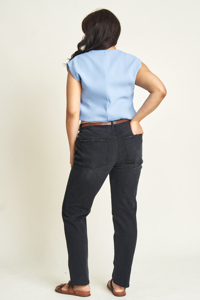 Back view of a curvy model in black low-rise jeans, emphasizing the tailored design and flattering fit through the hips.
