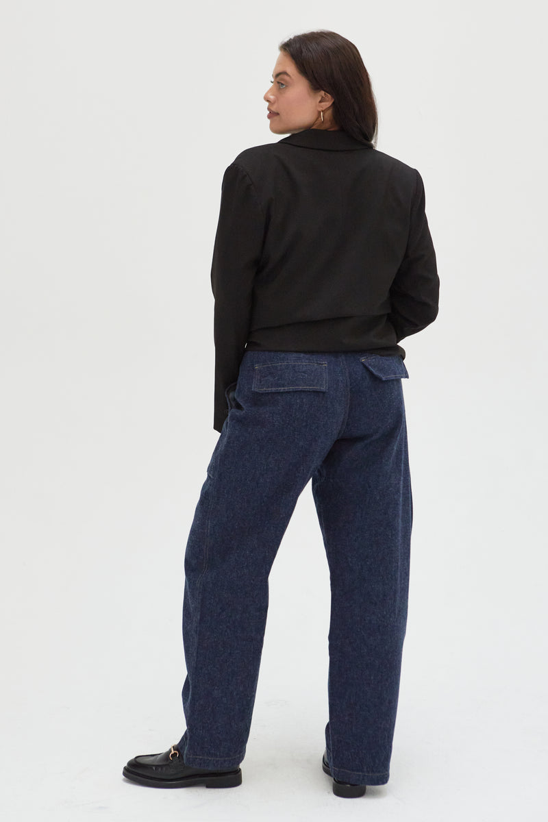 Back view of a plus-size model in dark indigo trouser jeans, highlighting the clean lines, tailored back pockets, and structured silhouette.
