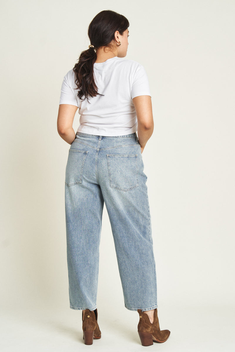 Back view of the model in light-washed barrel jeans, highlighting the relaxed silhouette and classic light wash.
