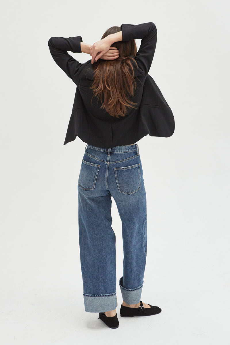 Back view of mid-rise wide-leg jeans in durable denim, showcasing structured pockets, a relaxed silhouette, and a cuffed hem for modern styling.