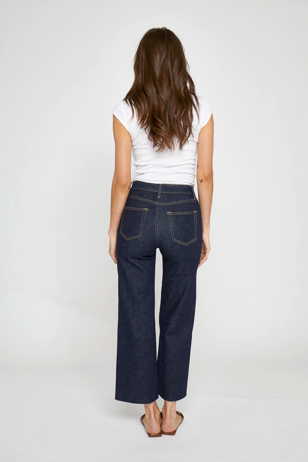 Back view of a model in wide leg cropped jeans, showcasing the relaxed fit and dark wash denim.
