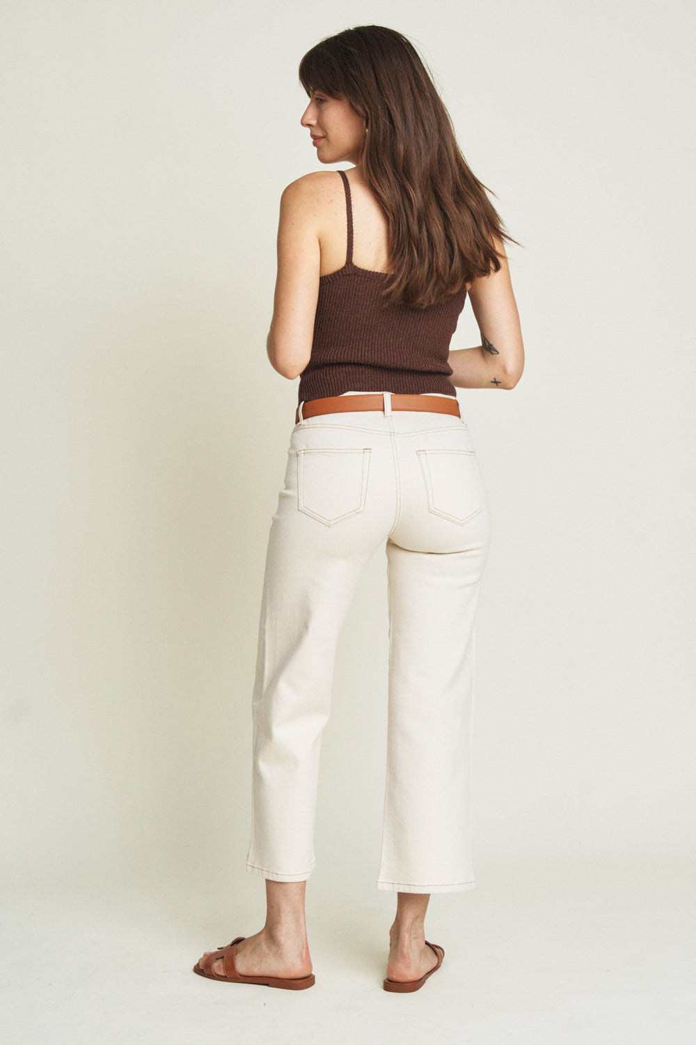 Back view of a model in ecru wide-leg ankle crop jeans, highlighting the structured silhouette and clean, minimalist design.